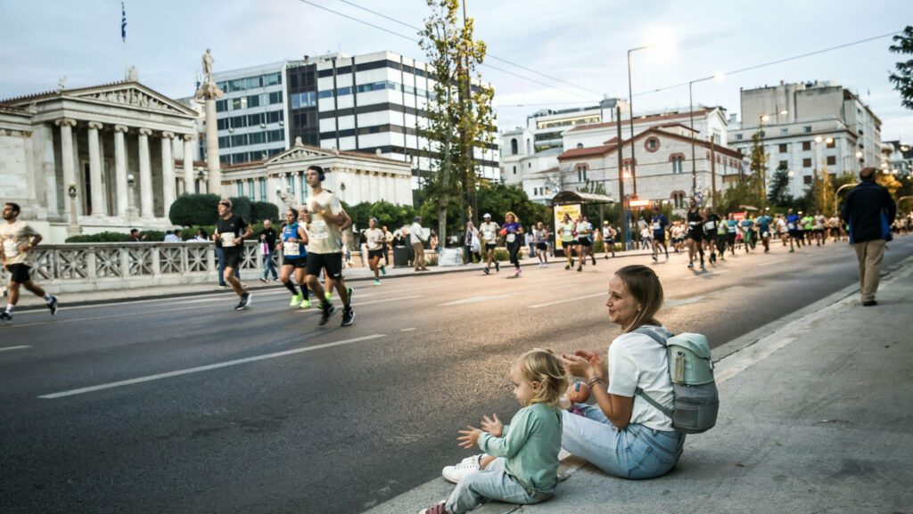 Eine Frau und ein Kind schauen einem Marathonlauf zu.