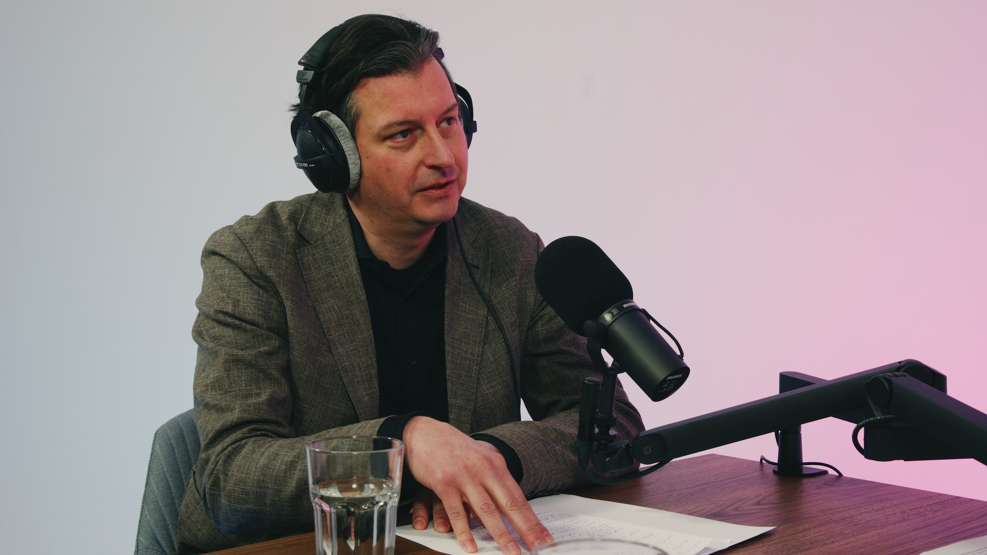 Eine Person sitzt mit Kopfhörer vor einem Mikrofon und spricht.