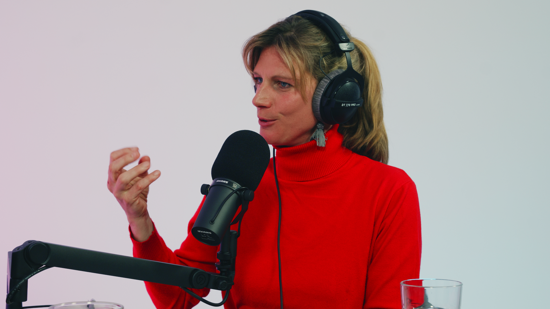 Eine Person sitzt mit Kopfhörer vor einem Mikrofon und spricht.