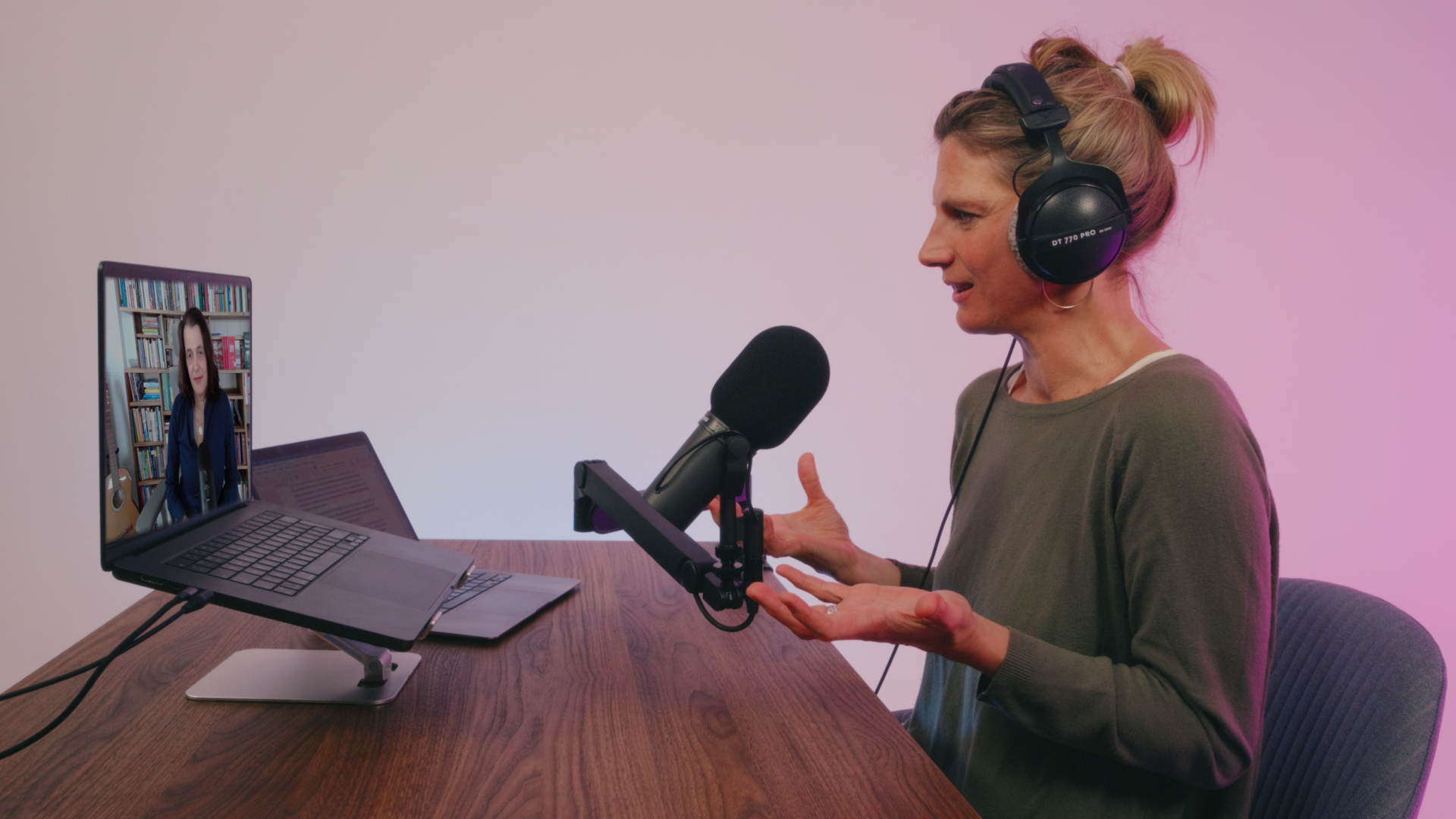 Eine Frau blickt auf einen Laptop, vor ihr ein Podcast-Mikrofon.